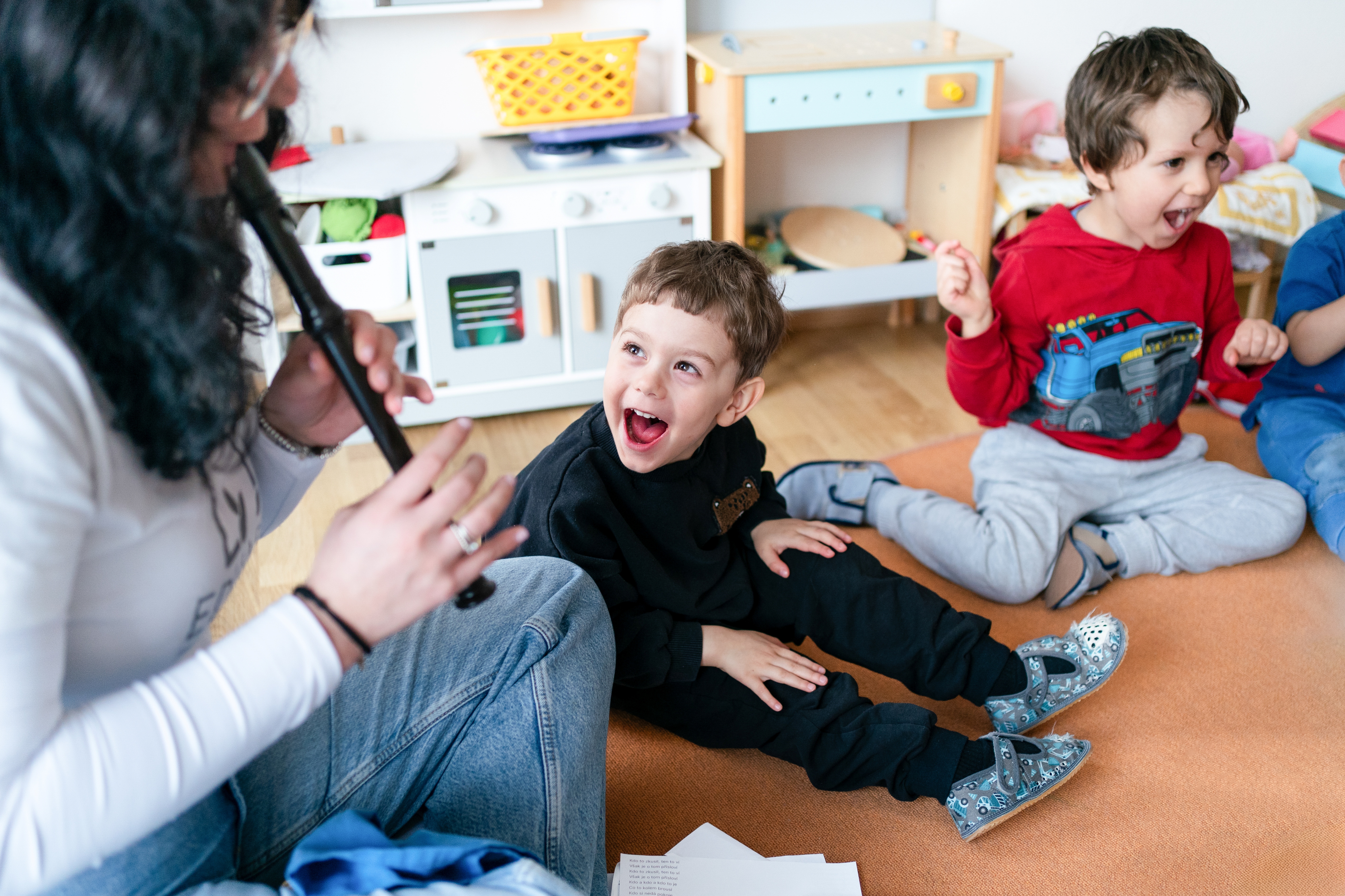 Učitelka si hraje s dětmi na zemi ve školce EduArt